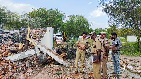 Police personnel and others stand near the fireworks factory where an explosion killed at least 10 people including four women, in Virudhunagar.