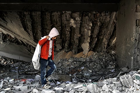 A boy walks with a sack while searching for debris to be salvaged from the rubble of a destroyed highschool in the Nuseirat camp for Palestinian refugees