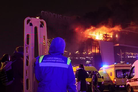 A medic stands near ambulances parked outside the burning building of the Crocus City Hall on the western edge of Moscow.