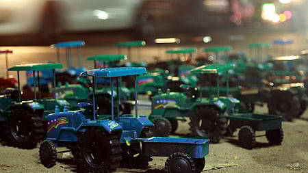 Tractor toys for children displayed on the roadside.