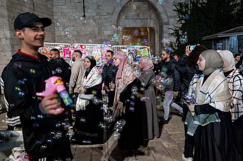 People walk in front of the Damascus gate in the Old City of Jerusalem, on the first day of Ramadan, Monday, March 11, 2024.