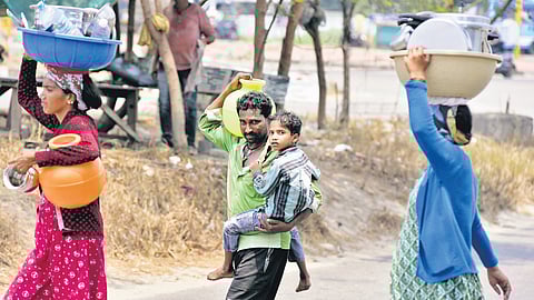 A migrant family from Chamarajanagar in Karnataka, who lives under Goshree Bridge, returns after collecting water for 
daily use on Thursday. The rising mercury levels have exacerbated water scarcity across the city. 