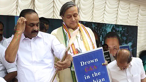Leader of Opposition V D Satheesan takes a look at the placard during the Congress dharna against Citizenship Amendment Act near Raj Bhavan in Thiruvananthapuram. MP Shashi Tharoor is also seen. 
