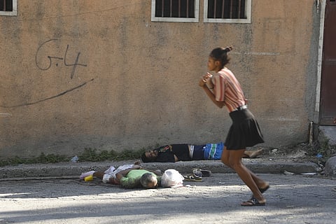 A woman walks past bodies of two men killed by unknown assailants in Port-au-Prince, Sunday, March 3, 2024.