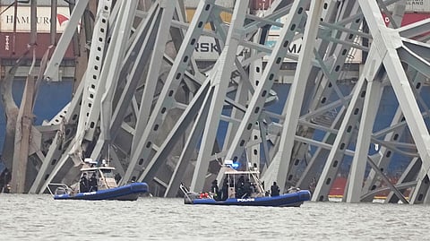 Police boats work around a cargo ship that is stuck under part of the structure of the Francis Scott Key Bridge after the ship hit the bridge Wednesday, March 27, 2024, in Baltimore.