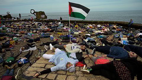 Pro-Palestinian demonstrators lie on the ground as they protest against Israeli attacks on Gaza, in San Sebastian, northern Spain, on Sunday, March 17, 2024.