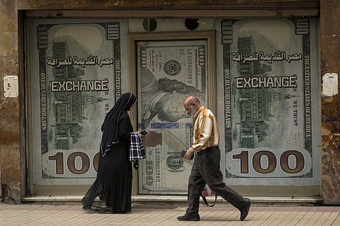 Egyptians walk past an exchange office in Cairo, Egypt, Wednesday, March 6, 2024.