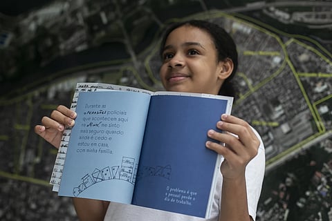 Myrella Victoria Viana dos Santos, 10, shows the book titled “I was supposed to be at school” that includes her experiences of living in the Mare favela of Rio de Janeiro.
