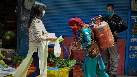 A Kashmiri woman is seen carrying an LPG cylinder on her back during the Covid-19 lockdown. 