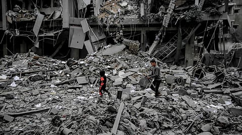 Palestinians walk amid the rubble of houses destroyed by Israeli bombardment in Gaza City.