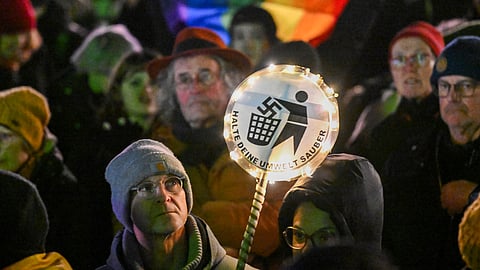 A man holds up a placard saying "Keep your environment clean" during a demonstration against right extremism and the policy of Germany's far-right Alternative for Germany (AfD) party, on January 16, 2024, in Cologne, western Germany.