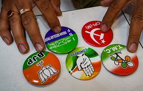 A shopkeeper shows brooches of different political parties on sale ahead of the upcoming Lok Sabha polls.