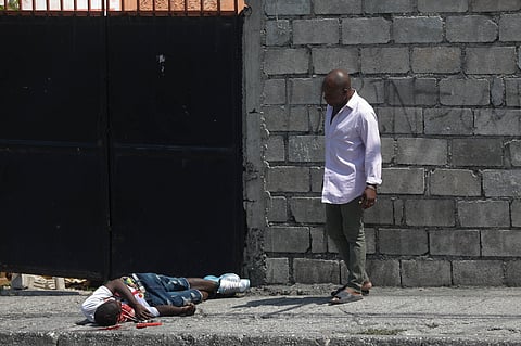 A resident looks at a body lying in the street in the Delmas area of Port-au-Prince, Haiti, Wednesday, March 20, 2024.