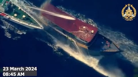 This frame grab from aerial video footage taken and released on March 23, 2024 by the Armed Forces of the Philippines, shows a vessel described by the Philippine armed forces as a China Coast Guard ship (L) deploying water cannon against the Philippine military-chartered civilian boat Unaizah May 4