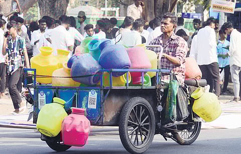 A man carries empty water pots on his motorised tricycle to fetch water at Egmore.