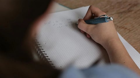 Image of a student writing an exam used for representational purposes only.