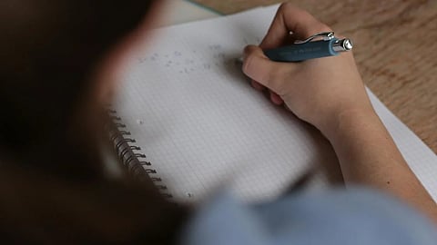 Image of a student writing an exam used for representational purposes only.