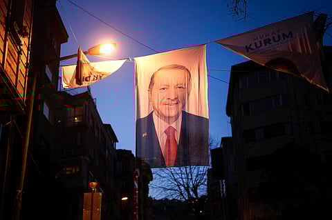 People walk under a campaign banner of Turkish President and leader of the Justice and Development Party, or AKP, Recep Tayyip Erdogan, in Istanbul, Turkey.