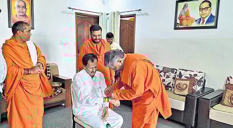 Sri Prasannananda Swamiji, the seer of Valmiki Gurupeetha, ties a holy thread around the wrist of Tumakuru Lok Sabha candidate SP Muddahanume Gowda in Tumakuru on Wednesday