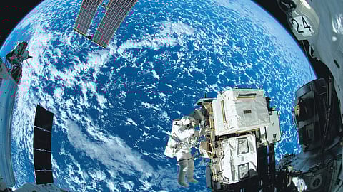 An astronaut fixes critical components outside the ISS, with the Earth for a backdrop