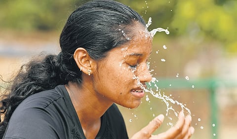 A girl splashing water on her face to beat the heat in Vijayawada