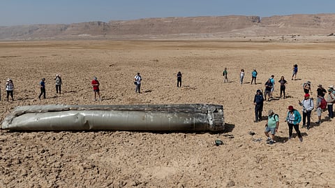 People gather around a component from an intercepted ballistic missile that fell near the Dead Sea in Israel, Saturday, April 20, 2024.