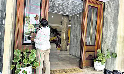 An official pastes notices of attachment on the entrance of the Vidyut Soudha, the head office of the power utilities, at Khairatabad in Hyderabad on Tuesday