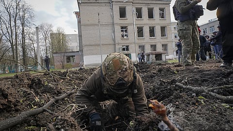 A military expert examines the site of a Russian bombing that killed several people in Kharkiv, Ukraine.