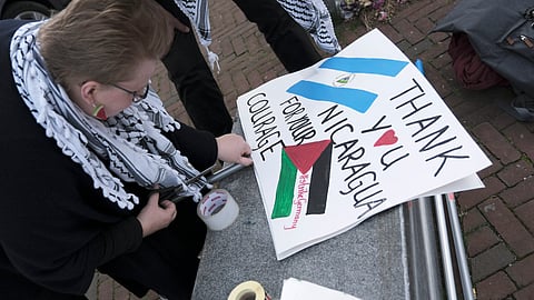 A pro-Palestinian activist works on a protest poster near the International Court of Justice, or World Court.