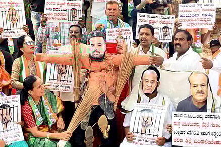 Congress leaders protest and burn photos of JD MP Prajwal Revann alleging his involvement in the sexual harassment case. 