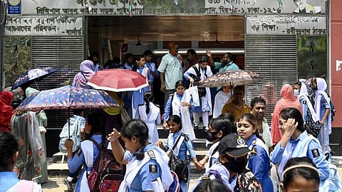 Students leaving their school compound carry umbrellas on a hot summer day in Dhaka on April 28, 2024, amid the ongoing heatwave. 