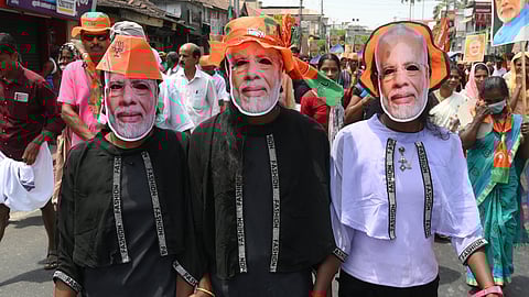 Children wear masks with pictures of Narendra Modi during a road show in Wayanad.