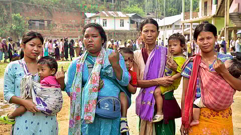 Voters carrying their children show their fingers marked with indelible ink after casting their votes for the first phase of Lok Sabha elections in Meghalaya on Friday, April 19, 2024.