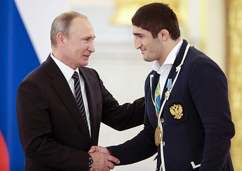 Russian President Vladimir Putin, left, shakes hands with Russia's Abdulrashid Sadulaev, gold medalist for the men's 86-kg freestyle wrestling competition, during an awarding ceremony for Russia's Olympians in Moscow's Kremlin.