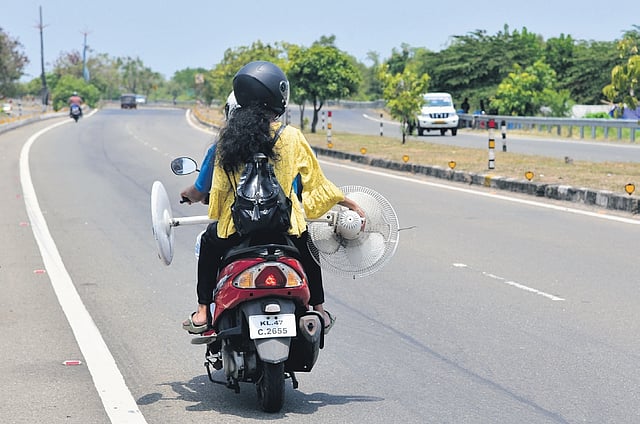 A woman carrying a pedestal fan on a two-wheeler in Kochi. With mercury level going up, residents are opting for various methods to beat the scorching heat 