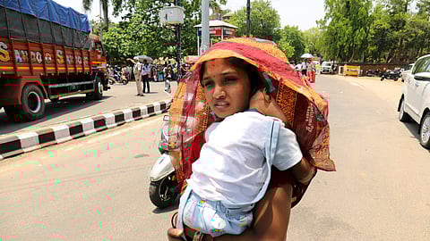 Mother cover her child's head with saree to protect from heat wave in Bhubaneswar on Friday. 