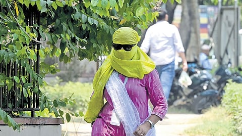A woman commuter covers her face with stole and sunglasses.