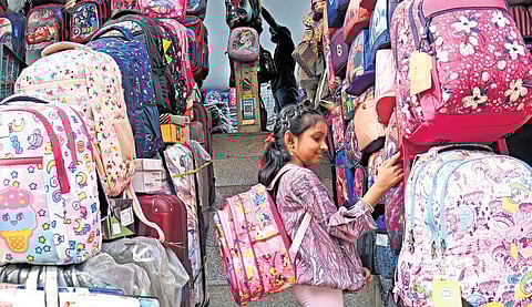 With schools reopening in the coming days, a girl checks out new schoolbags at a store in Bengaluru on Tuesday .