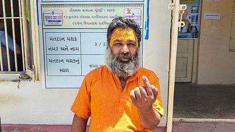 A man shows his inked finger after casting his vote at a polling station set up in the Gir forest, Banej.
