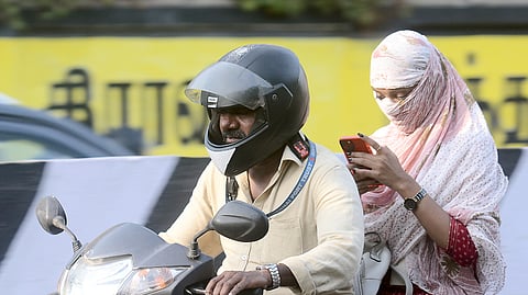 A woman covers her face with a shawl to shield herself from the hot and humid weather conditions in Chennai on May 2, 2024.