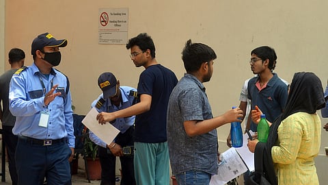 Aspirants undergoing a security check before entering a NEET exam centre.