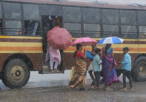 Commuters holding umbrellas get off a bus amidst the rains, in Kanyakumari district. (Representative Image)