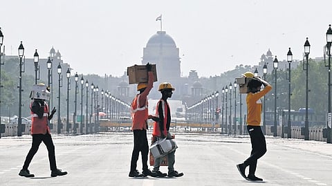 Amid heatwave conditions, workers pass the Kartavya Path.