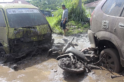 A man walks past the wreckages of cars and a motorcycle swept away by a flash flood in Agam, West Sumatra, Indonesia, Sunday, May 12, 2024.