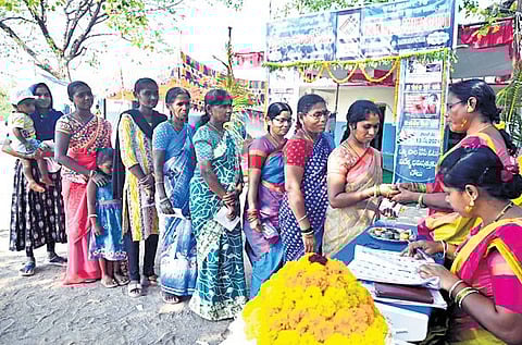 Self-help group members apply kumkum and turmeric paste and offer bangles to women voters at a polling station in Shankarapatnam