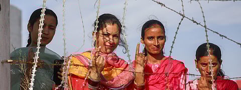People show their inked fingers after casting their votes during Lok Sabha elections.
