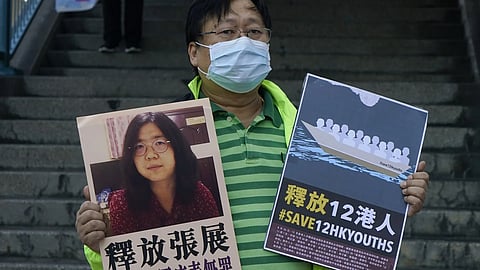 A pro-democracy activist holds placards with the picture of Chinese citizen journalist Zhang Zhan outside the Chinese central government's liaison office, in Hong Kong, Monday, Dec 28, 2020.