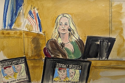 Stormy Daniels testifies on the witness stand as a promotional image for one of her shows featuring an image of Trump is displayed on monitors in Manhattan criminal court, Thursday, May 9, 2024.