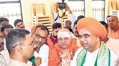 Dingaleshwar Swami of Shirahatti Bhavaikya Peeth argues with an election flying squad officer after he was stopped from holding a meeting of religious heads without obtaining prior permission, in Hubballi on Saturda.