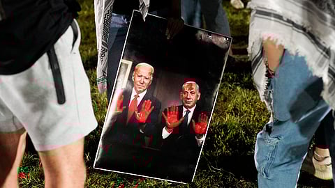 Pro-Palestinian protesters hold a sign depicting President Joe Biden and Israeli Prime Minister Benjamin Netanyahu with blood on their hands, on the campus of Ohio State University on May 1, 2024, in Columbus, Ohio.